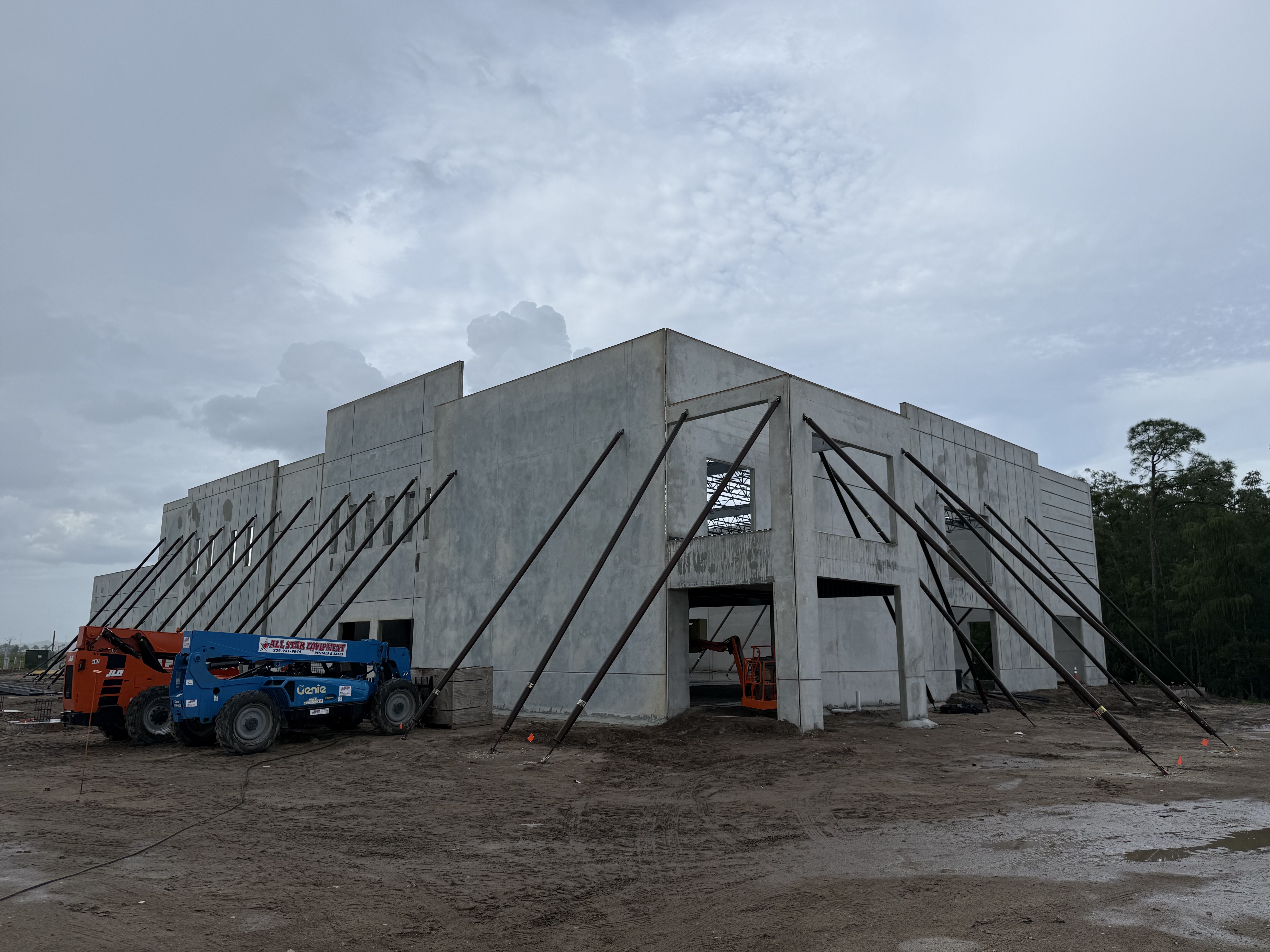 Rising concrete structure with wall supports and construction equipment at Palms Manor
